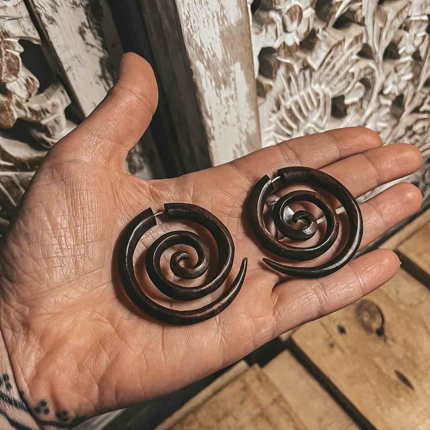 wooden spiral earrings fake gauge medium size in a hand