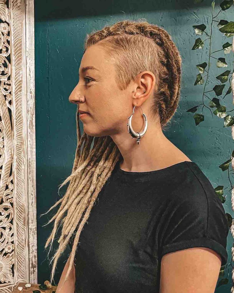 Blonde dreadlocks style with a shaved side on female with large silver hoope earring