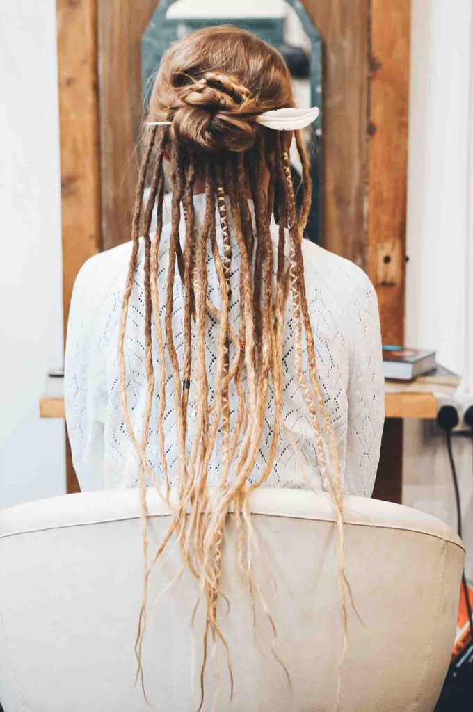 lady sitting on a salon chair with a Partial Blonde Dreadlocks style and a bone hairstick